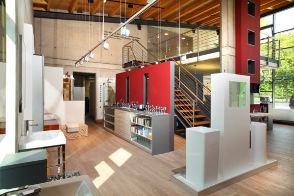 Badausstellung Modern Innenraum mit Holzdecken, roten Wänden und einer Treppe im Hintergrund.
