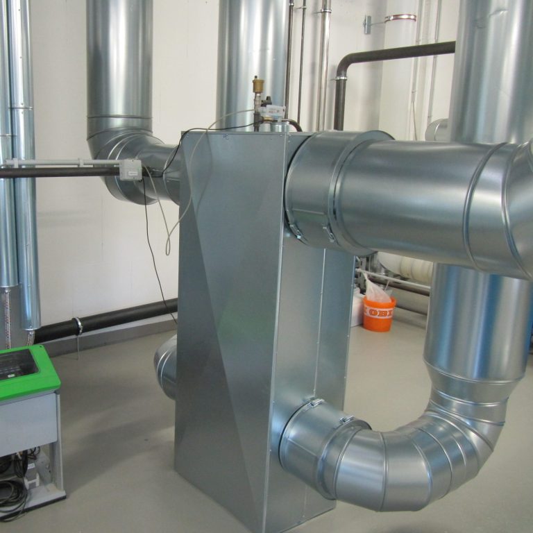 Blauer Heizkessel in einem technischen Raum mit Rohren und Ventilen.