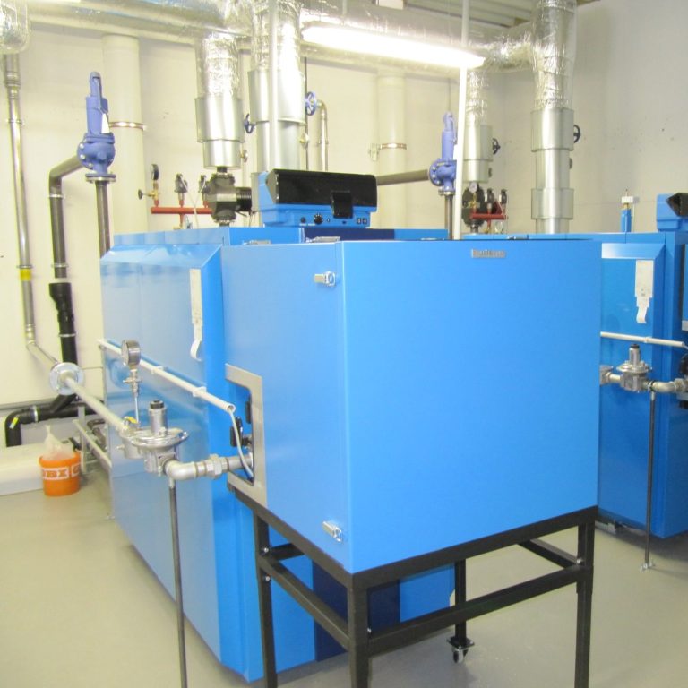 Blauer Heizkessel in einem technischen Raum mit Rohren und Ventilen.